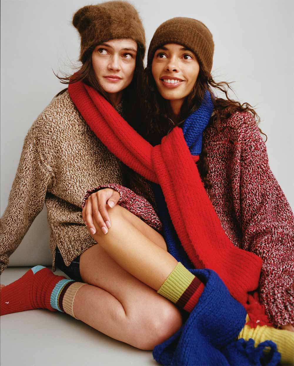 Two brunette women in oversized winter knit jumper, scarf and socks